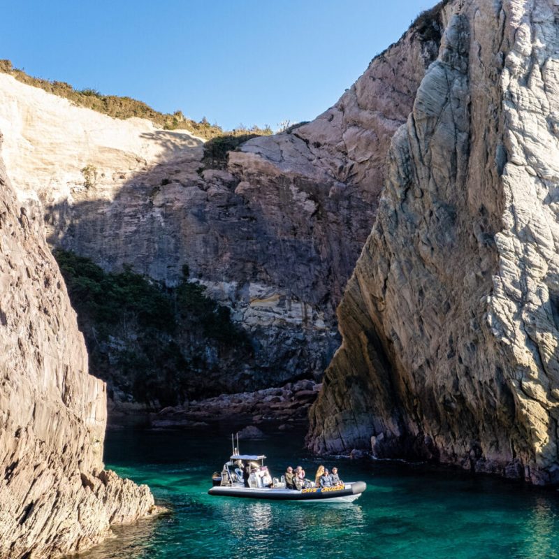 a rocky cliff with water and a mountain in the background